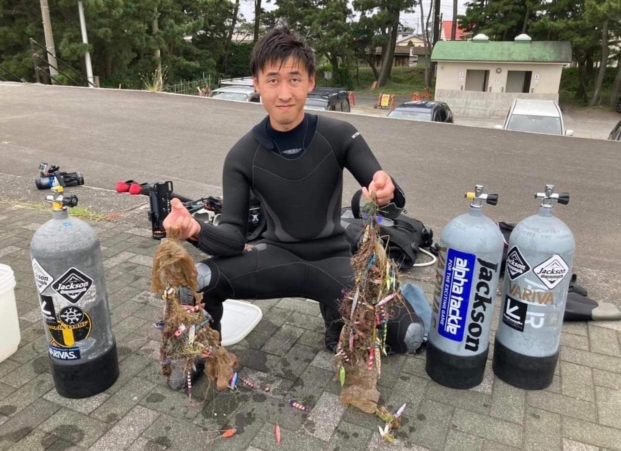 回収したルアーと釣り糸を持つダイバー